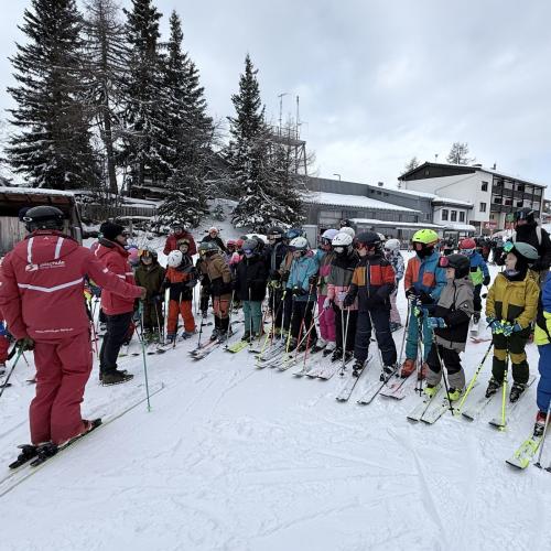 Kinder stehen nebeneinander in einer Reihe vor den Schilehrern