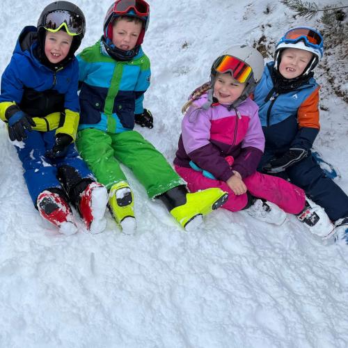 KInder sitzen im Schnee