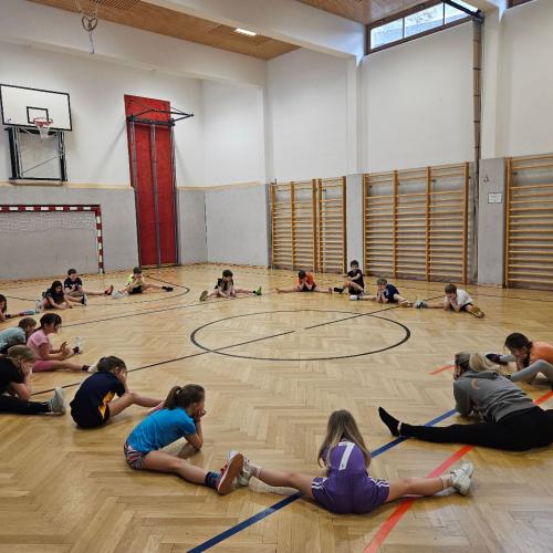 Kinder machen im Kreis Dehnungsübungen am Boden