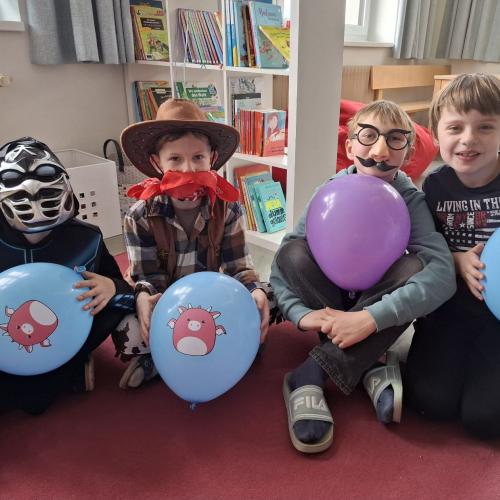 Verkleidete Buben mit Luftballons in den Händen sitzen am Boden