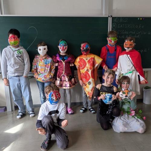 Verkleidete Kinder stehen und knien vor der Tafel