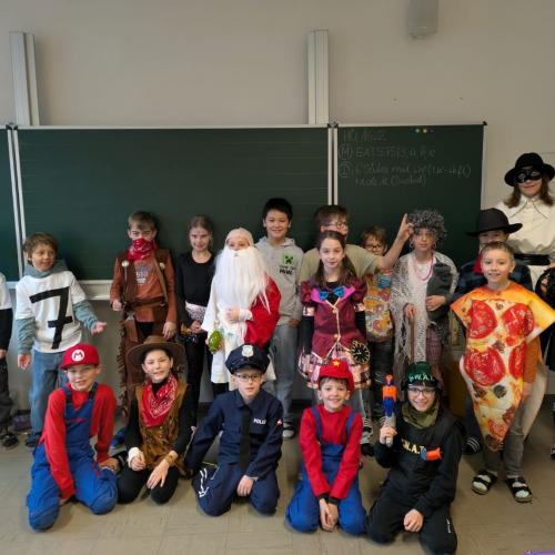 Verkleidete Kinder und Lehrerin stehen, knien vor der Tafel