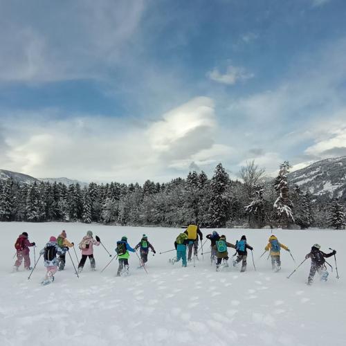 Kinder laufen mit Schneeschuhen über das Feld