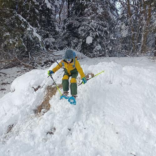 Kind springt mit Schneeschuhen über Hügel