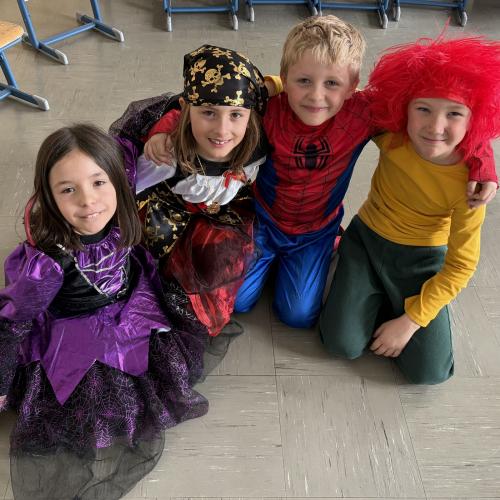 Vier verkleidete Kinder sitzen zusammen am Boden