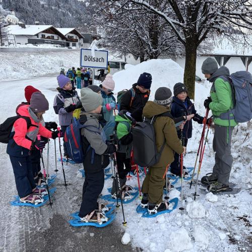 Kinder mit Schneeschuhen stehen vor der Rangerin