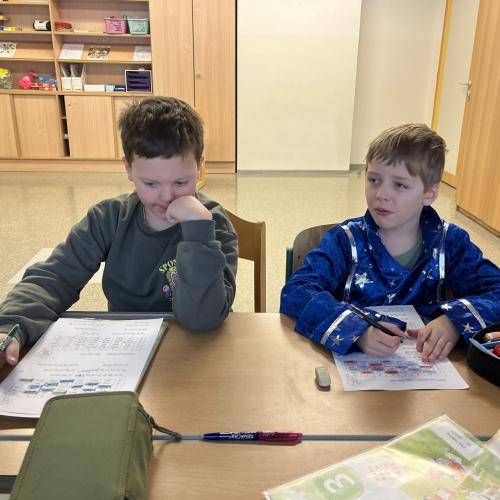 Zwei Buben sitzen am Schülertisch und schreiben