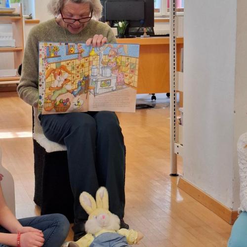 Büchereimitarbeiterin liest aus Bilderbuch vor