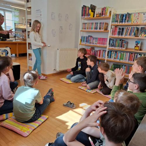 Kinder sitzen im Kreis am Boden, 1 Kind trägt Ei auf einem Löffel