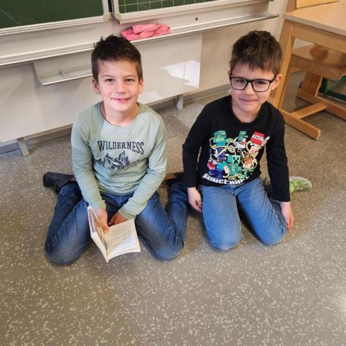 2 Kinder sitzen am Boden und lesen