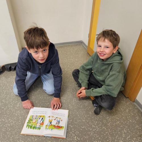2 Kinder sitzen am Boden und lesen