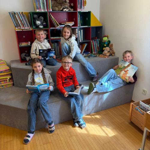 Kinder sitzen auf Sitzstufen und lesen