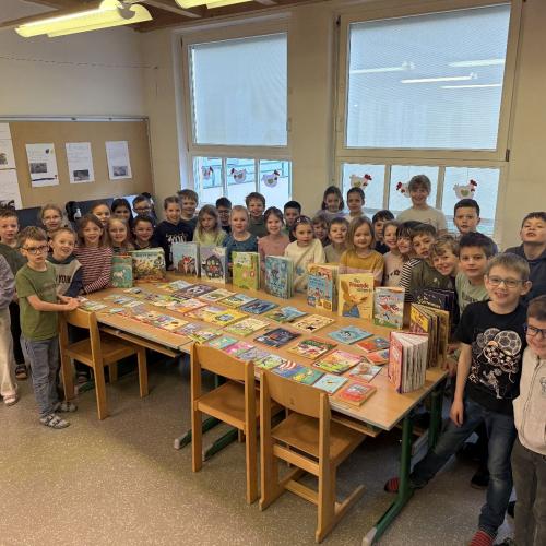 Kinder der beiden Klassen stehen um Schautisch mit Büchern