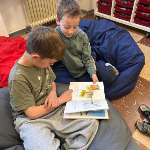 2 Kinder sitzen auf Sitzsäcken und lesen