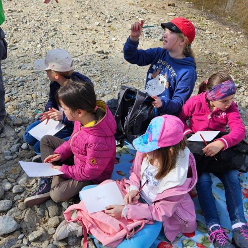 Kinder sitzen am Bach und untersuchen Wassertiere