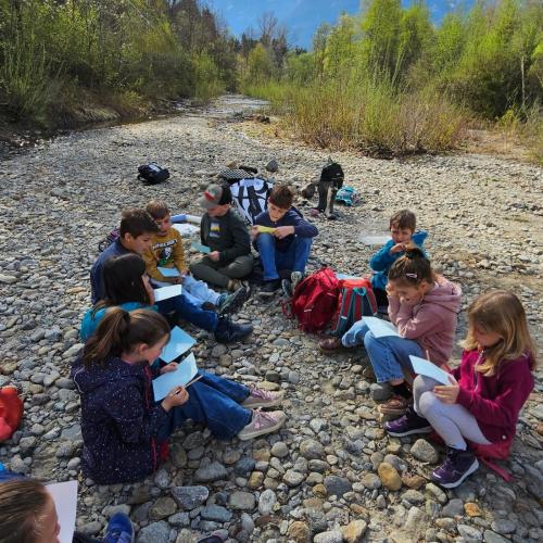 Kinder sitzen am Bach und zeichen Wassertiere