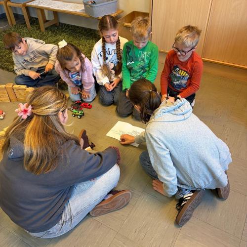 Kindergruppe sitzt am Boden und löst Rätsel