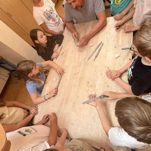 Bildhauer und Kinder sitzen am Tisch und feilen