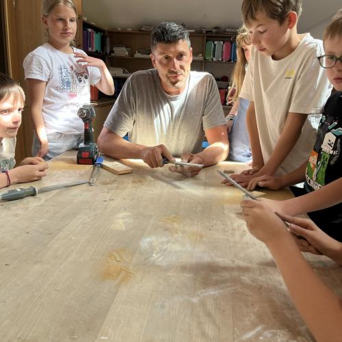Kinder schauen Bildhauer beim Feilen zu