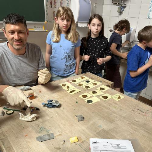 Bildhauer und KInder mit Werkstücken
