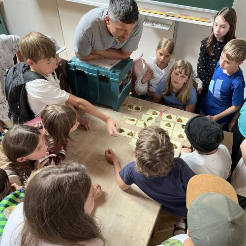 Bildhauer und KInder betrachten Werkstücke