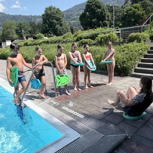 KInder stehen mit Schwimmbrett in der Hand in einer Reihe