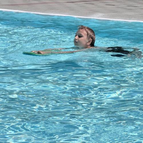 Kind schwimmt mit Schwimmbrett