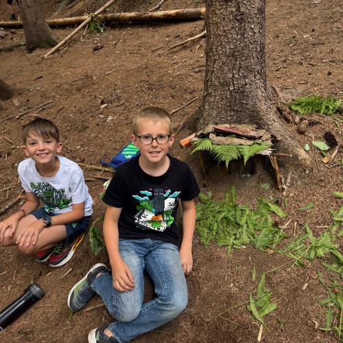 Kinder bauen aus Naturmaterialien einen kleinen Stall