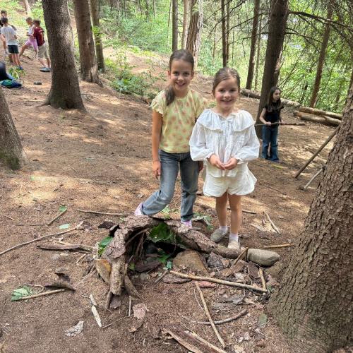 Kinder bauen aus Naturmaterialien eine kleine Asthütte
