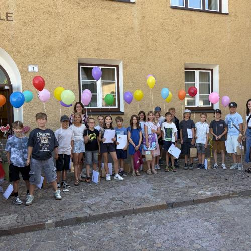 KInder der 4a-Klasse und Lehrerinnen stehen vor dem Schulhaus