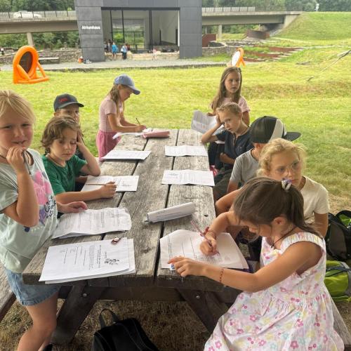 Kinder sitzen am Tisch und beantworten Quizfragen