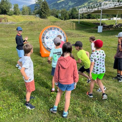 Kinder zielen mit Ball auf Plastikzielscheibe