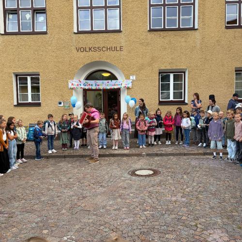 Schulkinder und Lehrpersonen vor dem Schulhaus