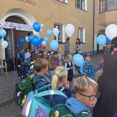 Erstklassler kommen mit Luftballonen in der Hand aus dem Schulhaus