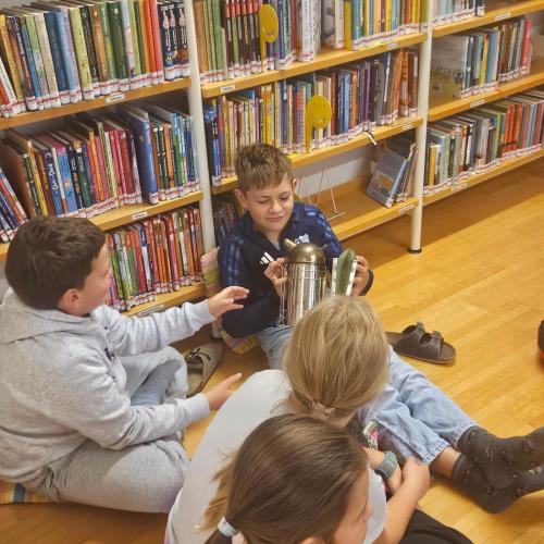Kinder sitzen am Boden, ein Kind hält Rauchgefäß in der Hand