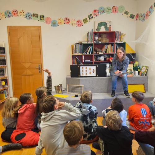 Kinder hören der Büchereimitarbeiterin zu