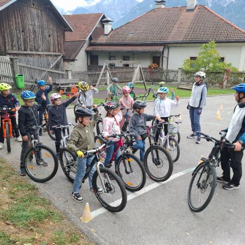 Kinder stehen mit den Rädern in der Gruppe und hören den FahrlehrerInnen zu