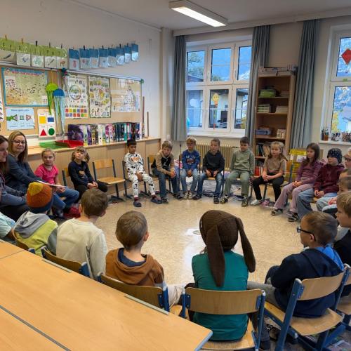 Kinder sitzen im Kreis und hören den Bäuerinnen zu