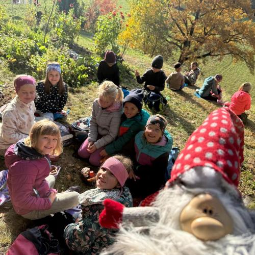 Kinder sitzen am Boden und jausnen, Klassenwichtel Seppl ist mit dabei