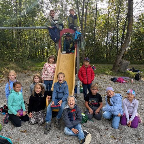 KInder sitzen, stehen im Sand und auf der Rutsche