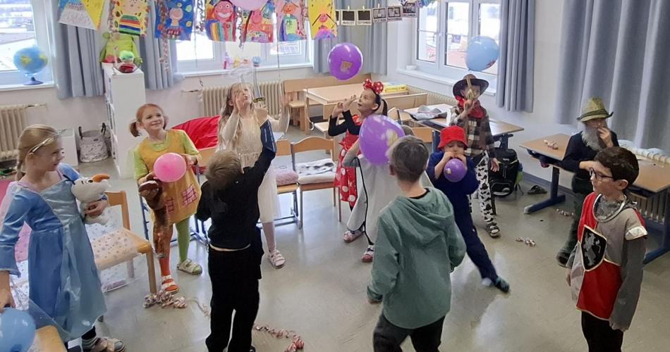 Verkleidete Kinder spielen mit Luftballons in der Klasse