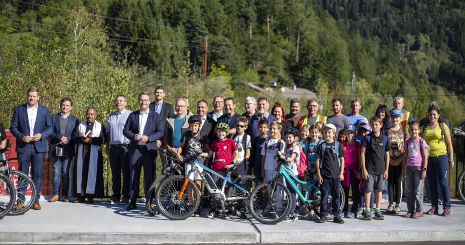 Festgäste und Schüler:innen mit Fahrrädern stehen am Brückenrand