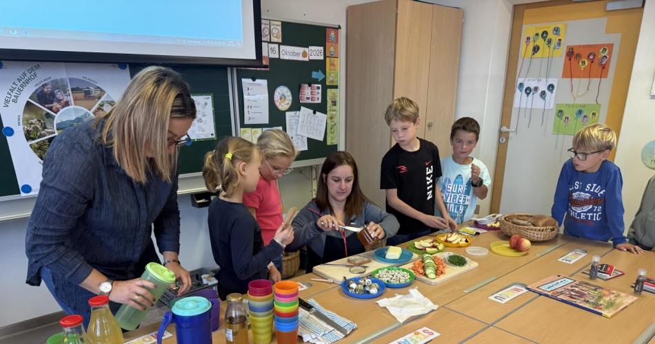 Kinder und Bäuerinnen beim Tisch mit Speisen und Getränken