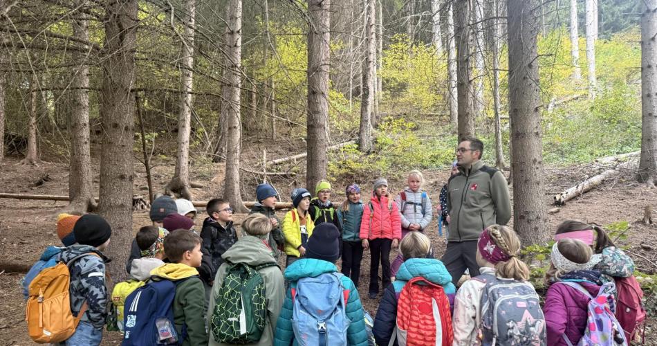 KInder stehen im Kreis um den Waldaufseher und hören ihm zu